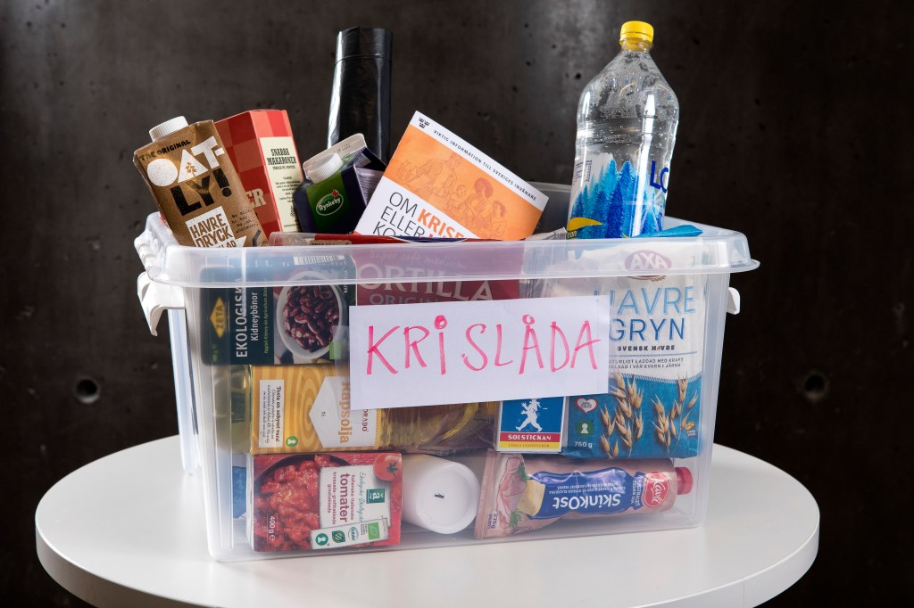 En låda med texten "Krislåda" fylld med varor som är bra att ha i krissituationer som vatten, stearinljus, MSB:s broschyr "Om krisen kommer".